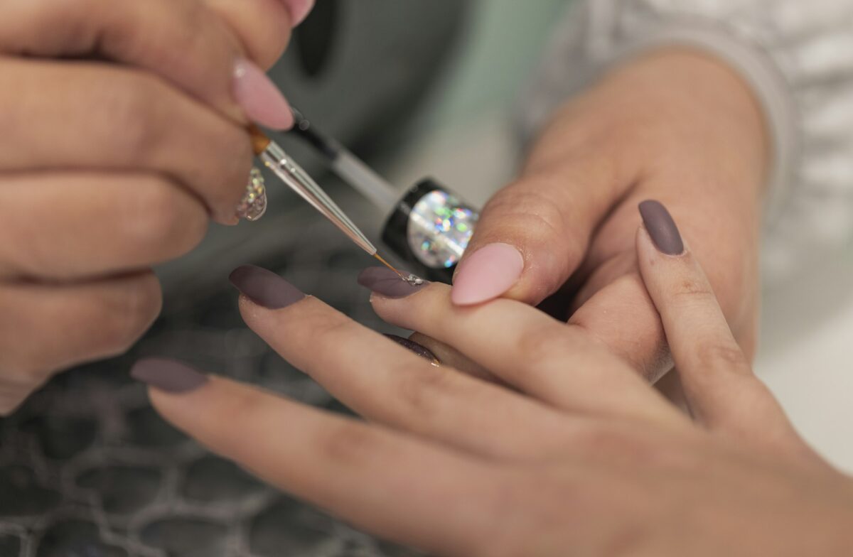 Nail stylist decorating customer's fingernails